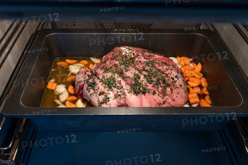 Preparation of a wild boar roast with spices and vegetables in a cast-iron casserole in the oven, Bavaria, Germany, Europe