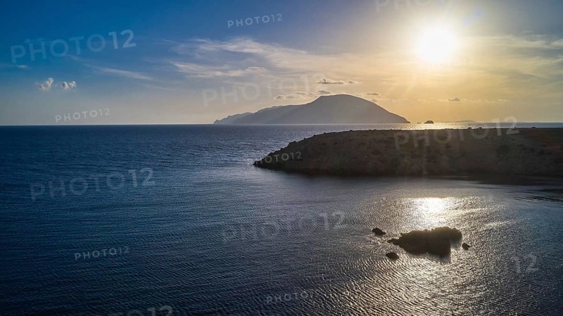 Sunset over the sea with a visible island and calm water, Kassos Island, drone shot, evening light, Paralia Agios Theodoros, Agios Theodoros Beach, southwest coast, Karpathos, Dodecanese, Greek Islands, Greece, Europe
