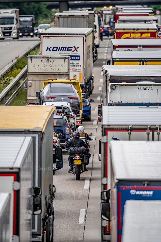 Motorcyclists squeeze past in the middle of the road between vehicles, in a 9 km long traffic jam on the A40 motorway eastbound, between the Dutch border near Venlo, in front of the Wankum junction, due to roadworks, traffic routing to one lane, many trucks in traffic jam, North Rhine-Westphalia, Germany, Europe