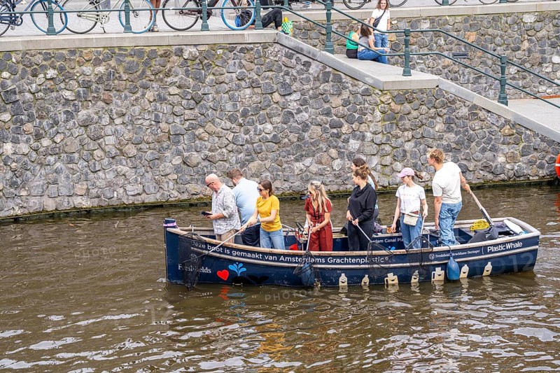 Plastic Whale boat in a canal in Amsterdam, passengers fish plastic waste out of the canals, tour through the canals of Amsterdam, collecting waste as an event, Netherlands