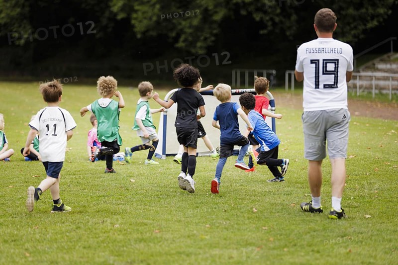 Volunteer coach trains children on the football pitch, Bonn, 19.06.2024
