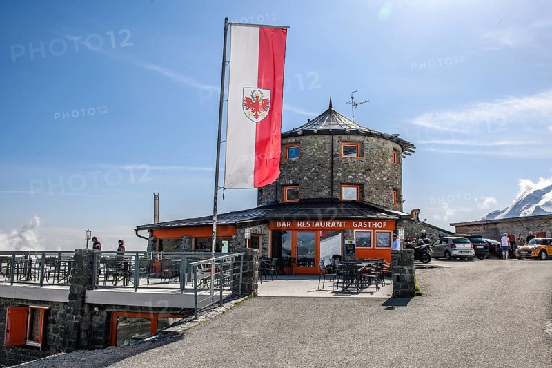 In front flag flag of South Tyrol behind it historic mountain hotel hotel restaurant bar inn alpine inn Tibetan style building at 2800 metres above sea level above the top of the Alpine pass Alpine pass road Stelvio Stilfser Joch, Stilfs, South Tyrol, Italy, Europe