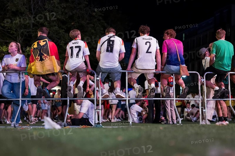 Fans with shirts of the German national team sit on barriers at the fan zone at the Brandenburg Tor after the 2-0 win in the round of 16 match between Germany and Denmark at the European Football Championship, Berlin, 29 June 2024
