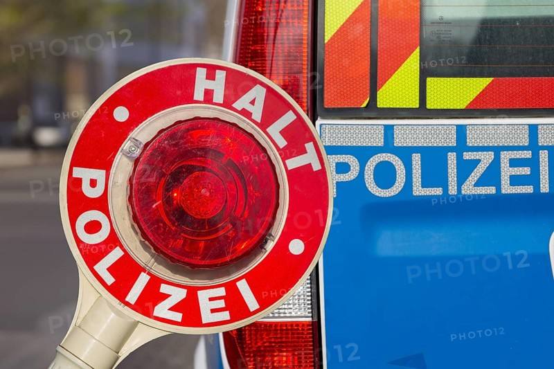 Police control: Close-up of a police trowel with the inscription HALT POLIZEI in front of a police vehicle (Composing)