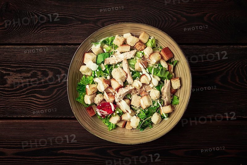 Fresh traditional Caesar salad, with chicken, on a wooden background, Top view, dark background, horizontal no people