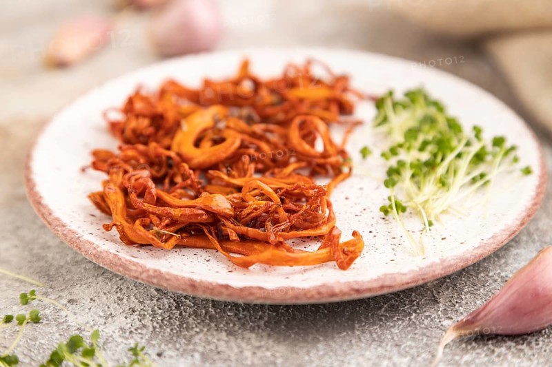 Fried Cordyceps militaris mushrooms on brown concrete background with microgreen, herbs and spices. Side view, copy space, selective focus
