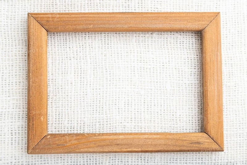 Wooden frame on smooth white linen tissue. Top view, flat lay, natural textile background and texture