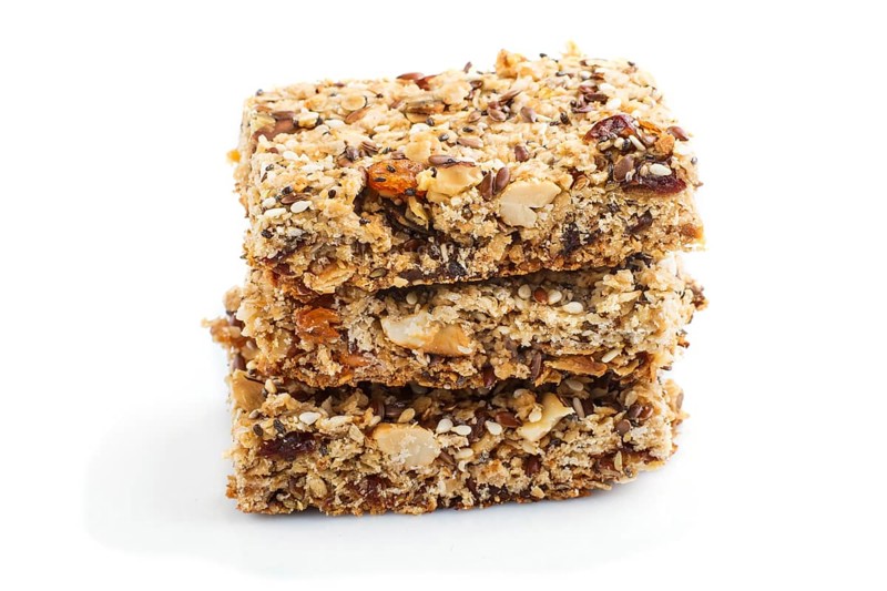 Homemade granola from oat flakes, dates, dried apricots, raisins, nuts isolated on white background. Side view, close up, macro