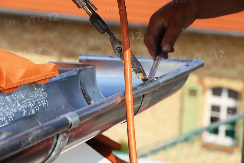 Roofer doing tinsmith work on a gutter
