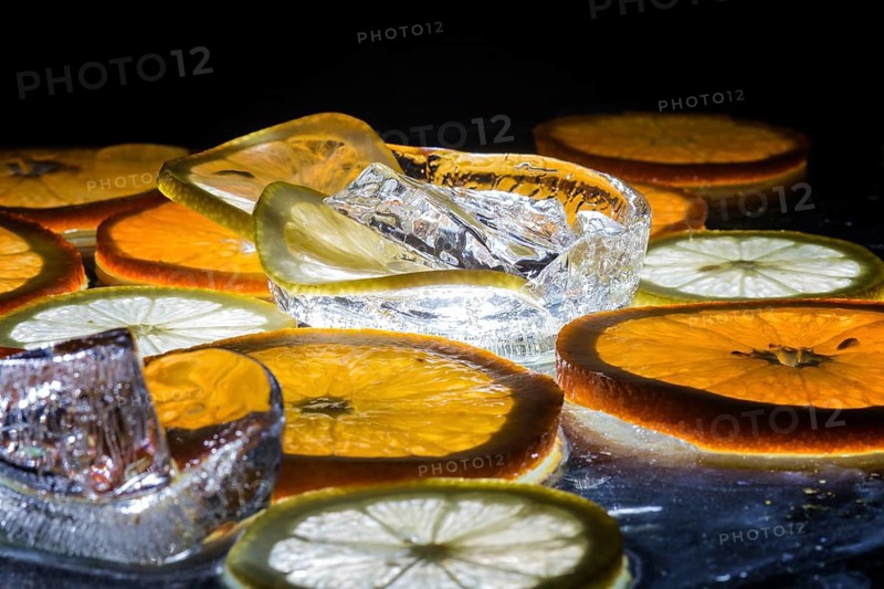 Transparent slices of fresh oranges and lemons on the glass with ice