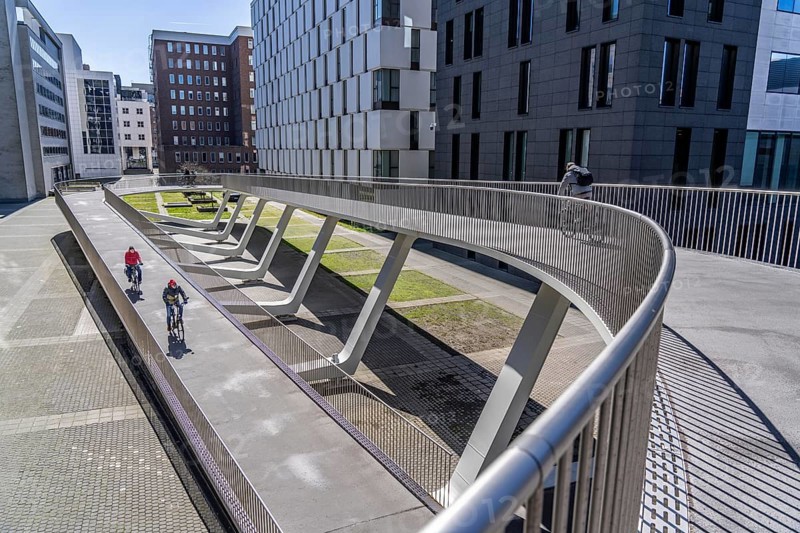 The Parkbruk, cycle and pedestrian bridge in the city centre of Antwerp, crosses a multi-lane city centre road with tram lines and thus connects two lively city districts Kop Spoor Noord and Eilandje, 140 metres of curved ramp on the western side for driving up and down, walking, Belgium, Europe