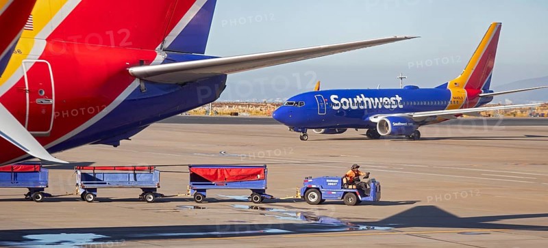 Oakland, California, A worker pulls bagge carts around Southwest Airlines planes at Oakland International Airport (OAK)