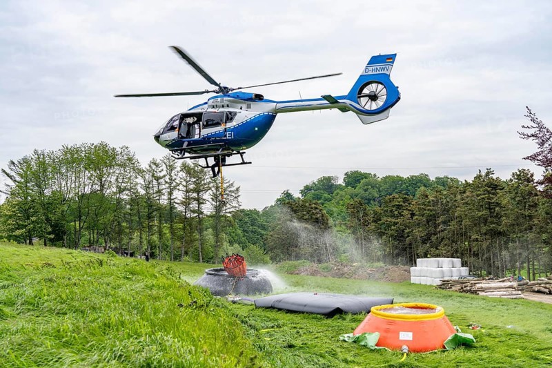Forest fire fighting exercise of the Essen fire brigade, the water supply was rehearsed over longer distances to the scene of the operation, water basins were set up there from which a fire-fighting helicopter can take water, Airbus H145 of the North Rhine-Westphalia police aviation squadron with Bambi Bucket extinguishing water tank, North Rhine-Westphalia, Germany, Europe