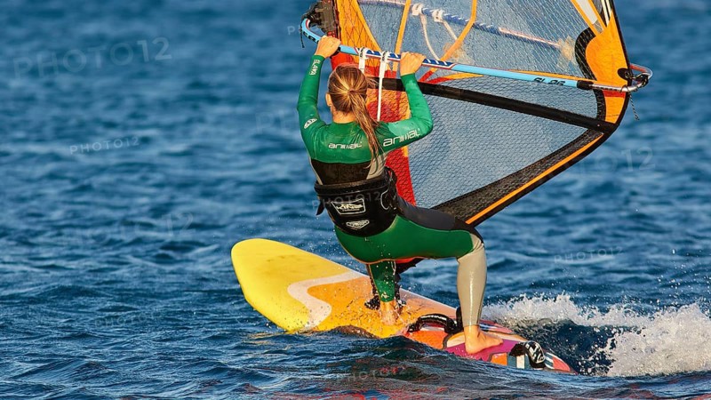 Woman in green wetsuit windsurfing on a yellow surfboard, windsurfer, Meltemi windsurfing spot, Devils Bay, Paralia Vatha, Vatha Beach, southeast coast, Karpathos, Dodecanese, Greek Islands, Greece, Europe