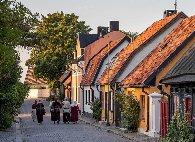 Visitors to the Medieval Week walk along a cobbled street in medieval dress, old houses, former Hanseatic city of Visby, UNESCO World Heritage Site, Gotland Island, Sweden, Europe