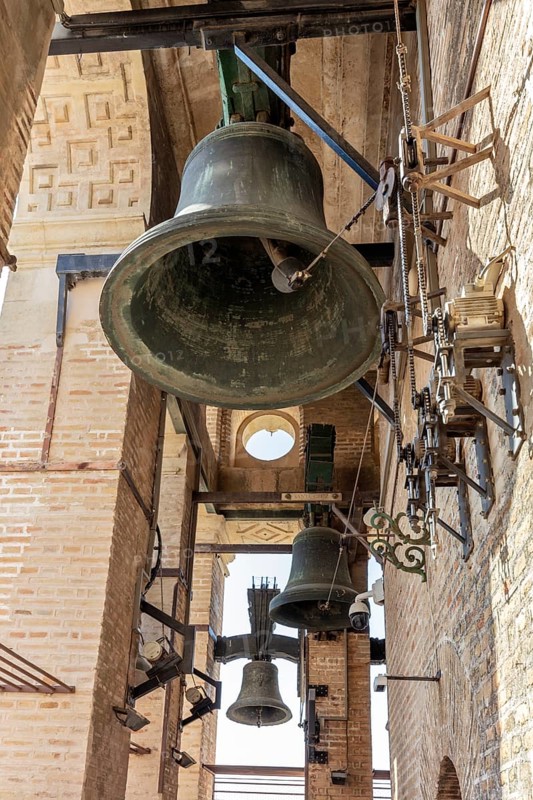 Close-up of an ancient bell tower with massive bells and metal structures, Seville