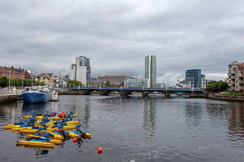 City view with skyscrapers and bridge over a river on which boats are floating, Belfast