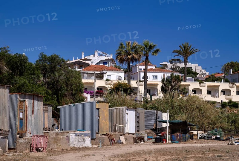 Corrugated iron huts, dwellings of labourers, behind them villas, holiday homes, contrast, poor, rich, fishing village Ferragudo, Algarve, Portugal, Europe