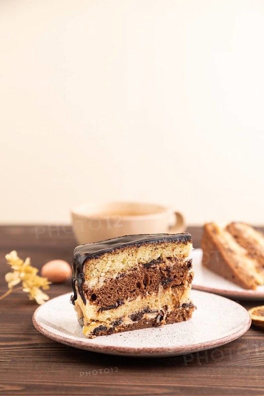 Chocolate biscuit cake with caramel cream, cup of coffee on brown wooden background. side view, close up, selective focus, copy space