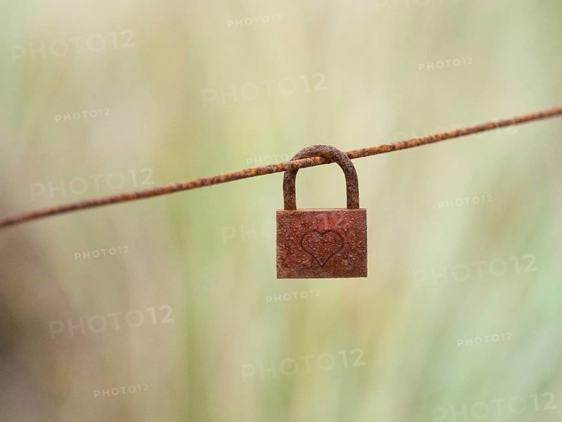 A Rusty Lock, with a heart inscribed upon it, hanging on a fence wire, island of Texel, Holland
