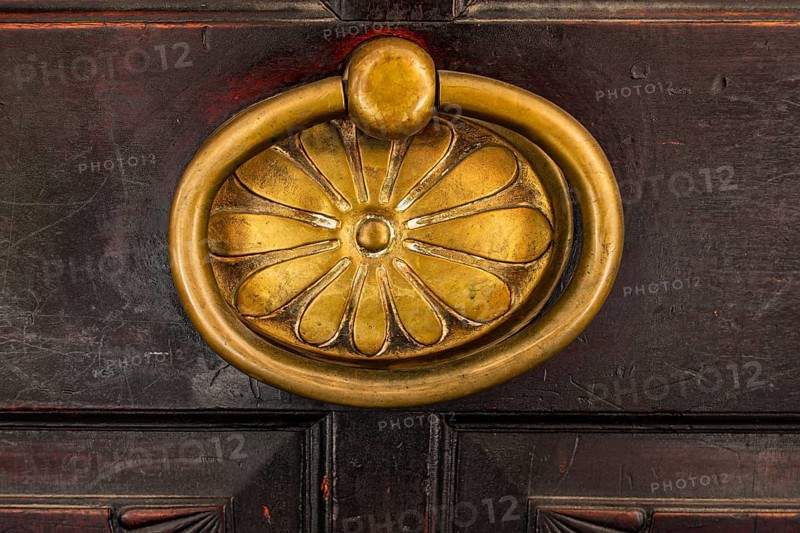 Historic brass door knob on a wooden door, background