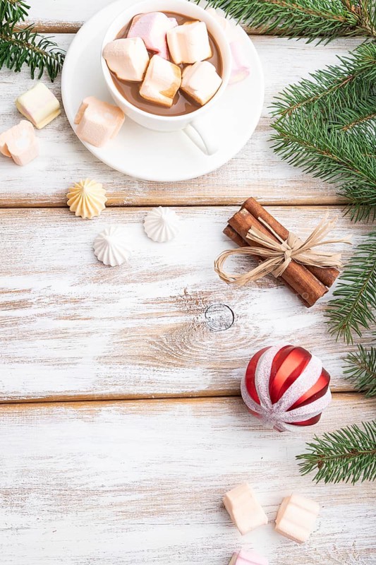 Christmas or New Year frame composition. Decorations, box, balls, cinnamon, ribbons, fir and spruce branches, cup of coffee, on a white wooden background. Top view, copy space, flat lay