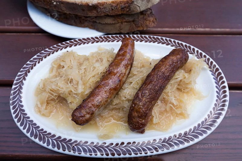 Two Nuremberg sausages with cabbage and bread on an oval plate in a garden restaurant, Bavaria, Germany, Europe