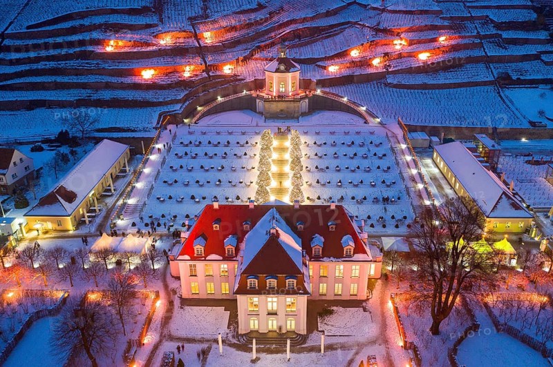 Aerial view of Wackerbarth Castle with castle park, belvedere and vineyards with snow and Christmas lights, Radebeul, Saxony, Germany, Europe