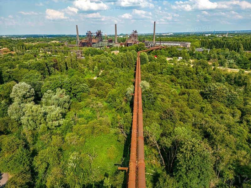 The Duisburg Nord Landscape Park, double blast furnace gas pipeline from the west View across the wilderness, a park area where nature is left to its own devices, to the steelworks, North Rhine-Westphalia, Germany, Europe