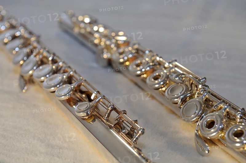 Close-up of two silver transverse flutes on a light-coloured surface