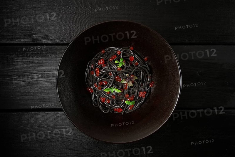 Black spaghetti with red caviar, pasta, on a black background, top view, no people
