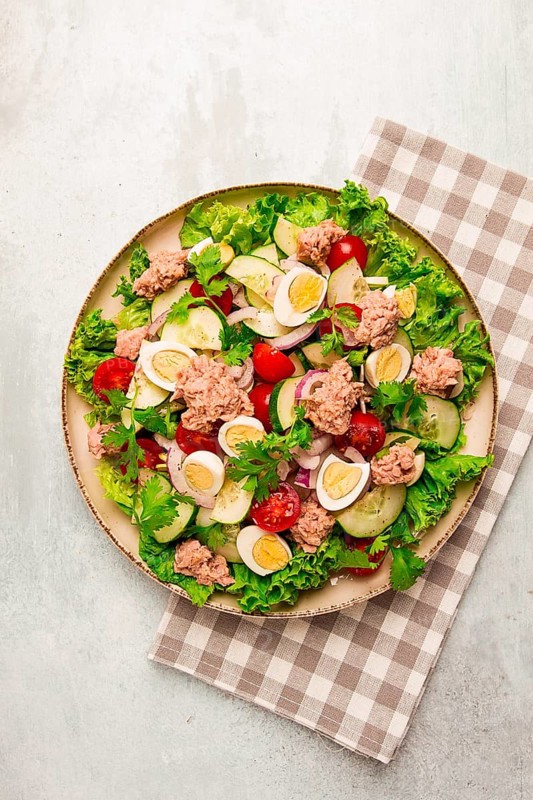 Tuna salad, vegetable salad with quail eggs, lettuce, red onion and cucumbers, on a light gray table, keto food, lifestyle, healthy eating, selective focus, top view, no people