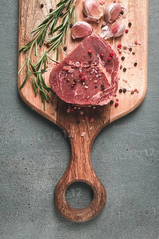 Fresh, raw rib eye steak, on a chopping board, top view, no people