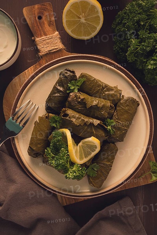 Dolma, cabbage rolls, grape leaves with filling, white sauce, lemon and herbs, rustic, selective focus, no people