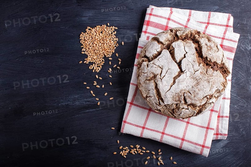 Yeast free homemade bread with whole rye and wheat grains on black wooden background. Top view, copy space