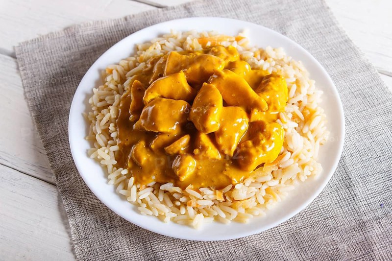 Rice with chicken curry sauce with cashew on white wooden background. top view, close up