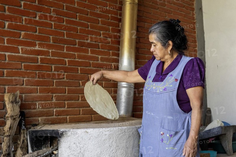Teotitlan del Valle, Oaxaca, Mexico, Rural women in the Tlacolula Valley of Oaxaca benefit from a microfinance loan program run by the nonprofit En Via Foundation. Women can get interest-free loans starting at 1500 pesos ($75 US) to start or expand a business. The organization also gives classes in business basics, English, and internet marketing. Microloan recipient Ernestina Sosa makes tortillas on her wood-fired comal. She sells them in the community, Central America