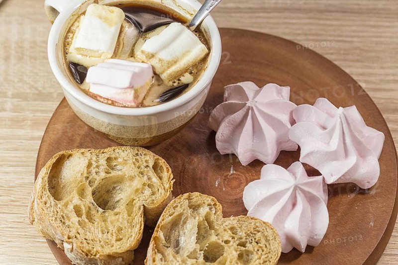 Chewing marshmallows, meringue and coffee cup on a wooden board and linen tablecloth