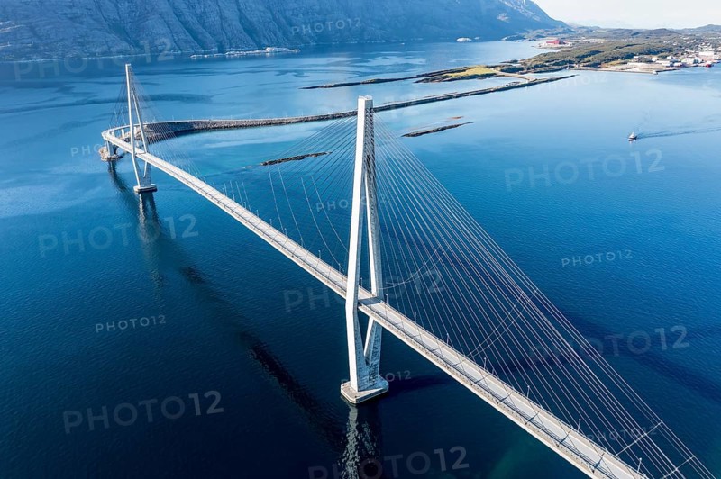 Aerial view of Helgeland bridge, connecting Sandnessjøen with the norwegian mainland, fishing boat passing by, Norway, Europe