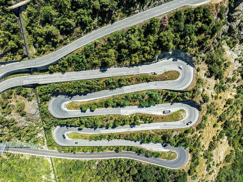 Mountain pass road with multiple hairpins, water pipeline, aerial view, drone shot. Valais, Switzerland, Europe