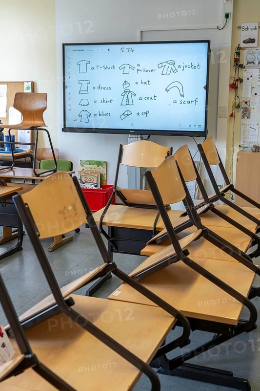 Classroom of a fourth grade, after school, the building is older but in good condition, modern teaching materials, interactive, digital whiteboard