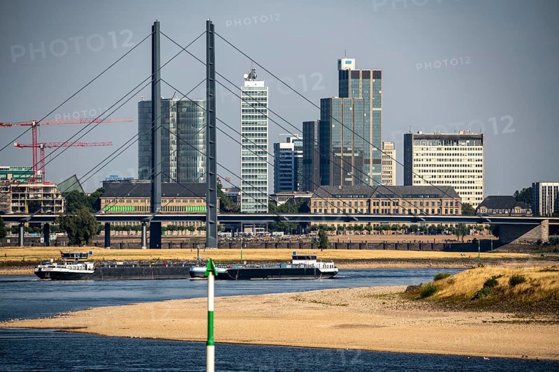 Rhine at Düsseldorf, extremely low water, Rhine level at 47 cm, falling, barge in front of the skyline with the Rheinkneibrücke bridge, sandbanks, freighters are only allowed to sail with very reduced cargo and very slowly, North Rhine-Westphalia, Germany, Europe