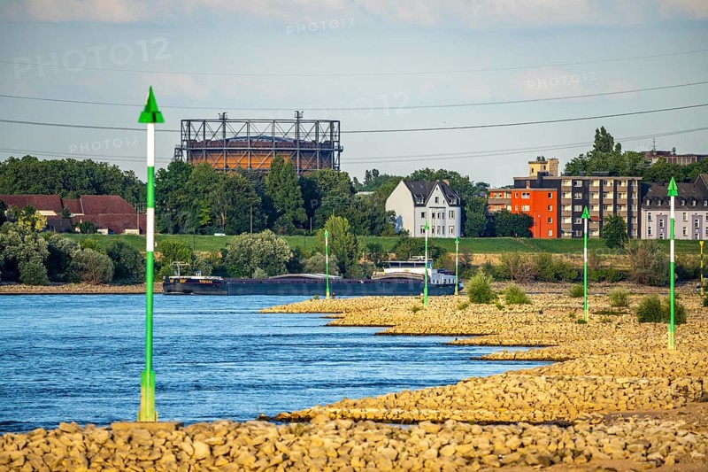 Cargo ship at low water on the Rhine near Duisburg-Homberg, view of Duisburg-Laar, houses on Deichstraße, gasometer of ArcelorMittal Hochfeld GmbH steel wire plant, 3.48 metres is normal, at the time of the photo only 2.58 metres level, but still far from the low level when restrictions for shipping enter, North Rhine-Westphalia, Germany, Europe