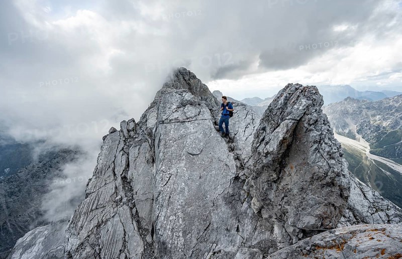 Mountaineer on a narrow rocky ridge on a steel cable, Watzmann crossing to Watzmann Mittelspitze, view of mountain panorama, Berchtesgaden National Park, Berchtesgaden Alps, Bavaria, Germany, Europe