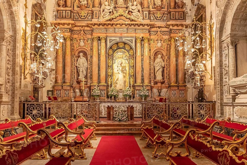 Opulent chapel with magnificent altar and elegant red benches, Seville