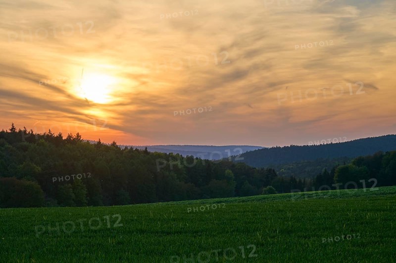 Sunset over a green meadow, surrounded by forest and hills under a cloudy sky, summer, Mönchberg, Mltenberg, Spessart, Bavaria, Germany, Europe