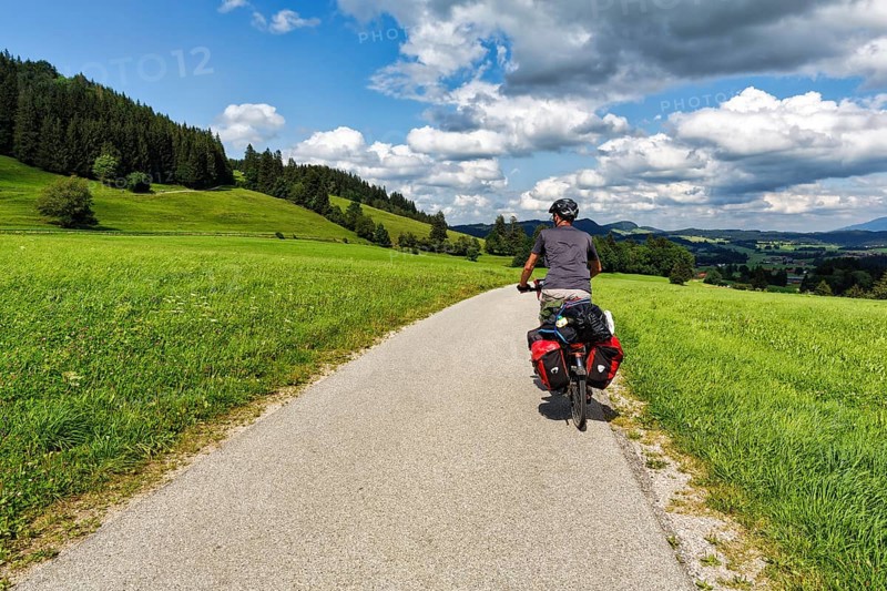 Cyclist riding on cycle path, hilly landscape with meadows, bicycle bags, panniers, Oberallgäu, Lake Constance Königssee cycle path, Lake Constance-Königssee cycle path, long-distance cycle path, long-distance cycle path, Germany, Europe