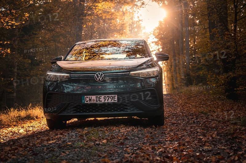 Car in the golden light of the evening sun on an autumnal forest path with leaves, electric car VW ID5, Gechingen, Black Forest, Germany, Europe