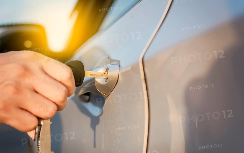 Hands with keys opening the car door. Close-up of hands opening the car door with the key. Concept of hands with keys opening the car door
