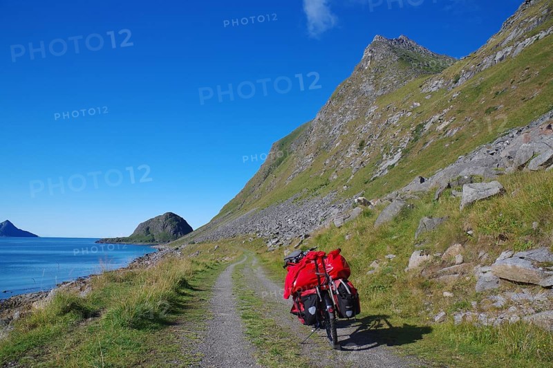Cycling on a gravel road along the sea with a view of mountains and a bright blue sky, cycling holidays, adventure holidays, Haukland, Leknes, vestavagoya, Nordland, Lofoten, Norway, Europe